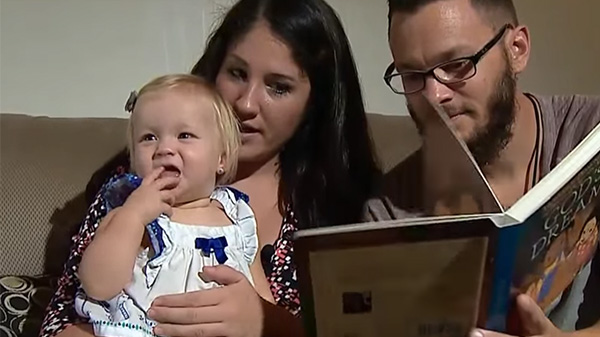 Na zdjęciu szczęśliwi rodzice czytają małej Rylan bajkę