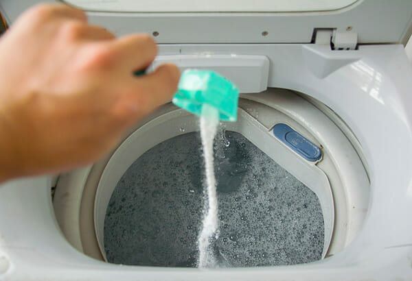 Na zdjęciu widać, jak ktoś dosypuje proszku do prania