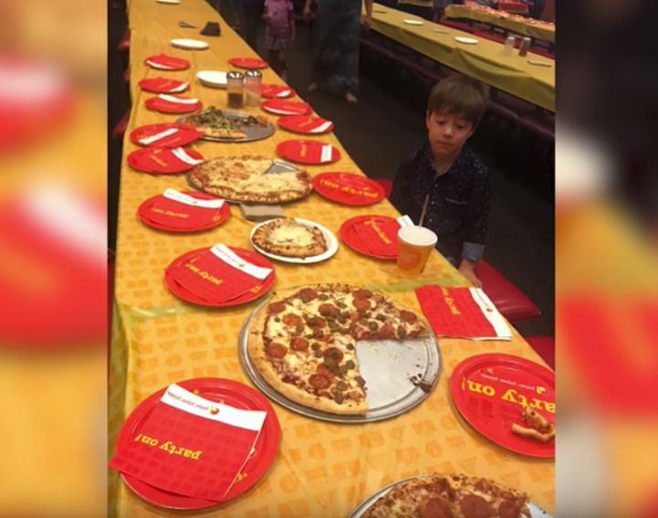 chłopiec siedzi przy stole z pizzą