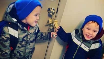 dwójka chłopców ubrana  granatowe czapki chwyta za kokardkę u drzwi