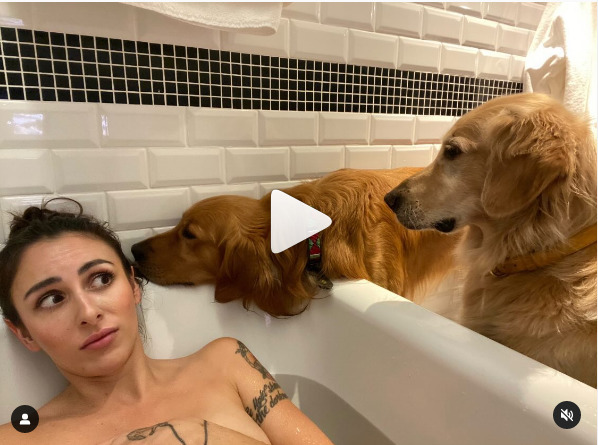 kobieta leży w wannie i stoją przy niej psy