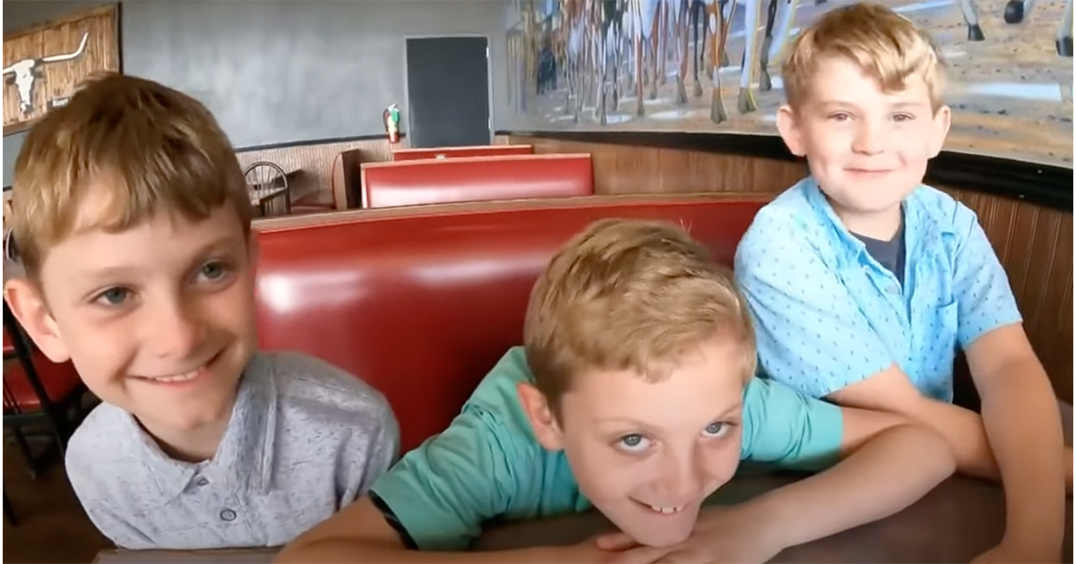 trzech chłopców siedzi na czerwonej kanapie