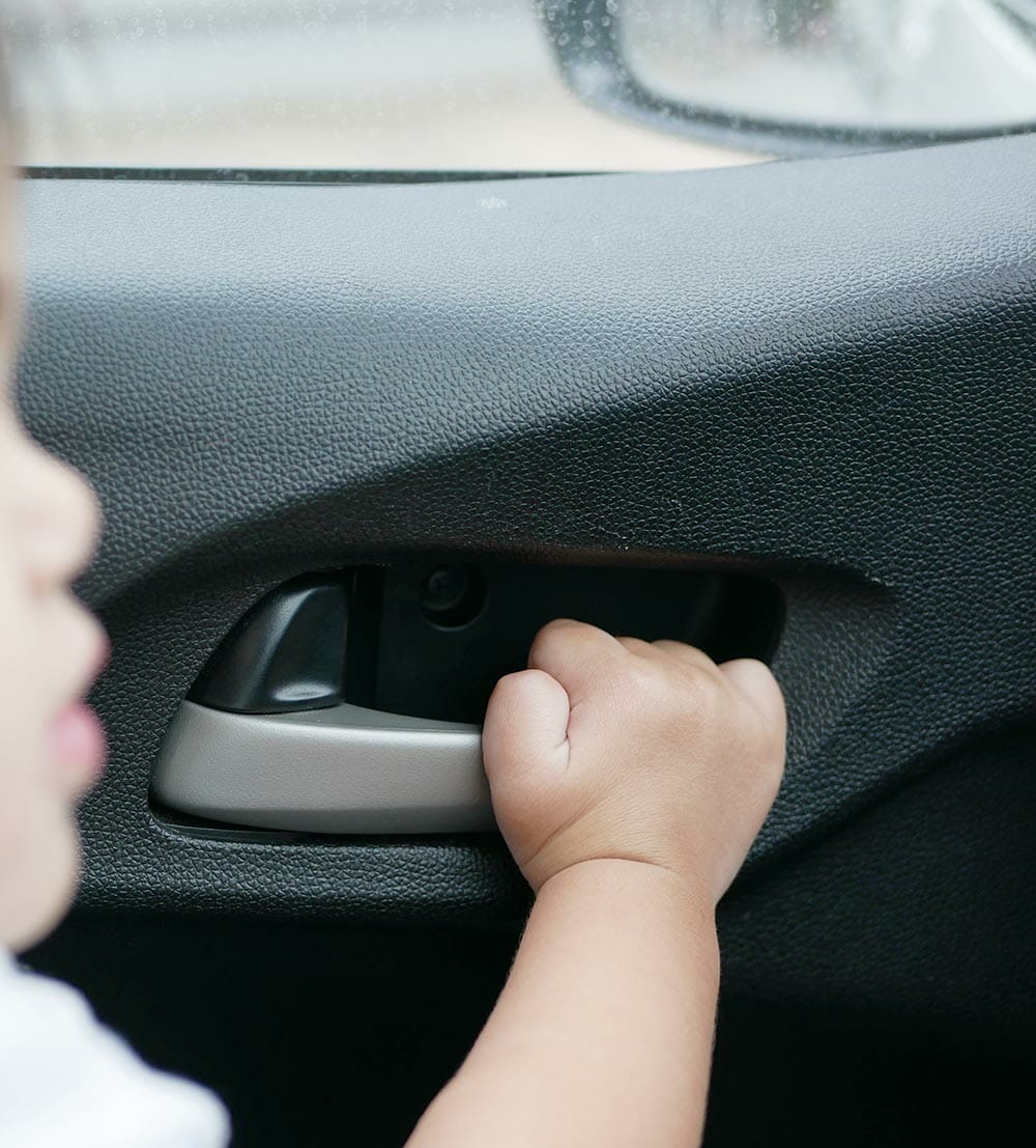 dziecko chwyta za klamkę w samochodzie