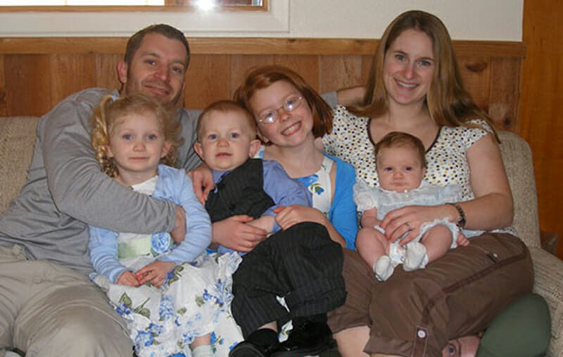 mężczyzna, kobieta i czwórka dzieci siedzą na kanapie