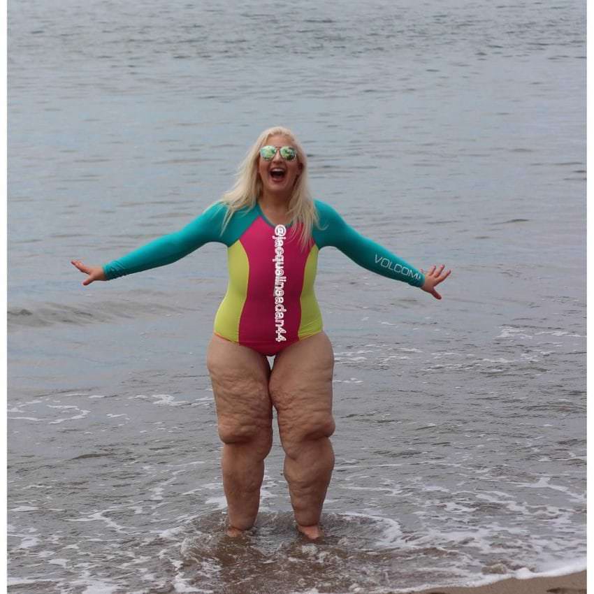 kobieta w jednoczęściowym stroju stoi w wodzie na brzegu morza